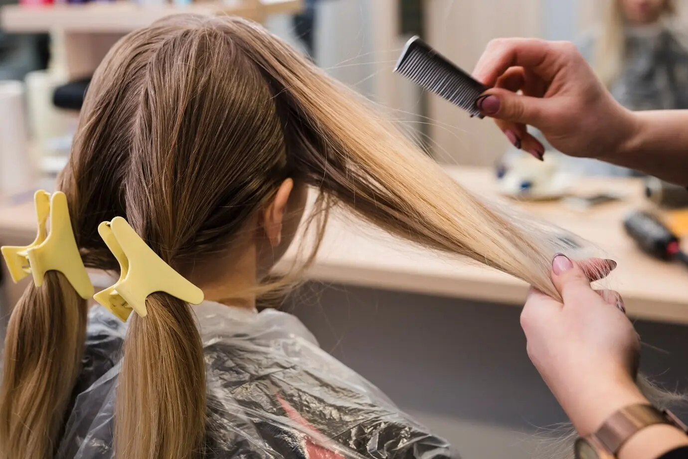A blonde girl is having her hair styled.