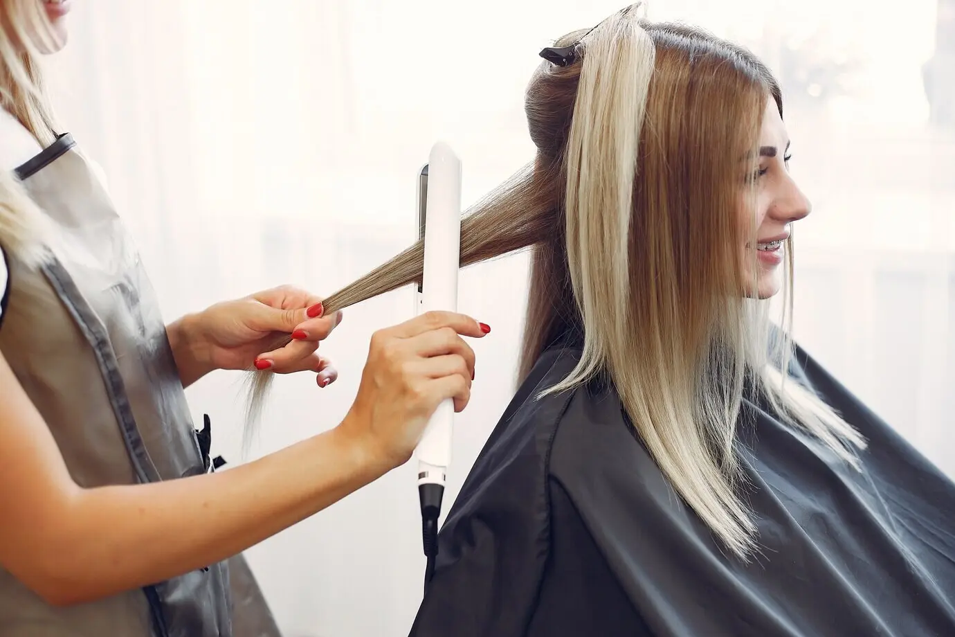 A hairdresser is styling her client's hair.