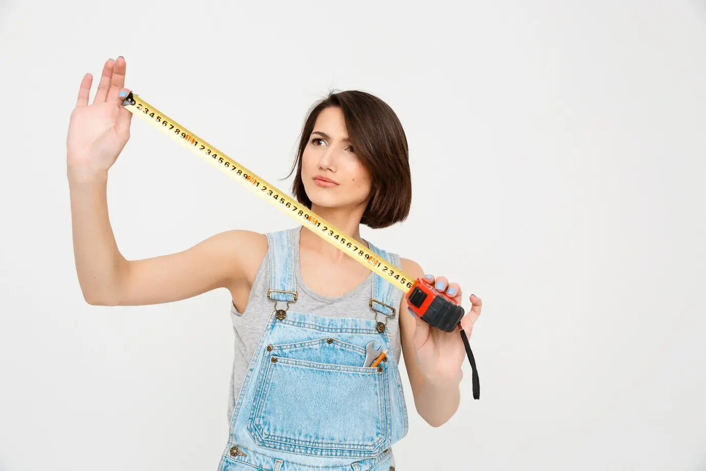 A cute woman renovates a house with a tape measure.